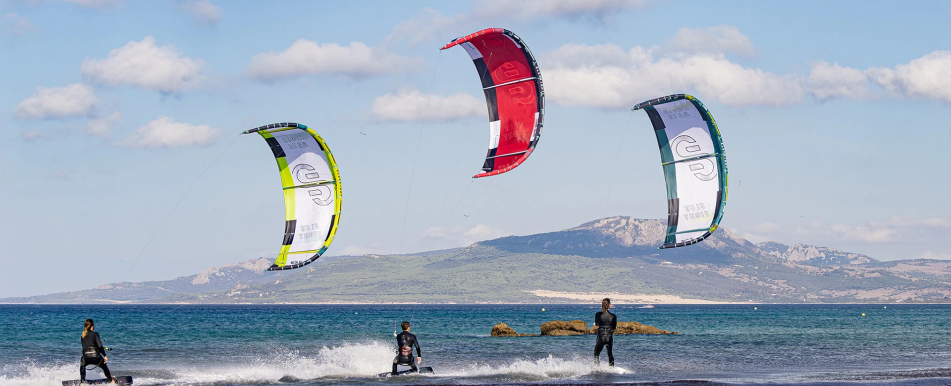 Trois kitesurfeurs avec leurs ailes Eleveight au bord de l'eau